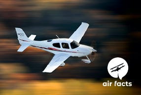 white plane flying over blurred background of trees